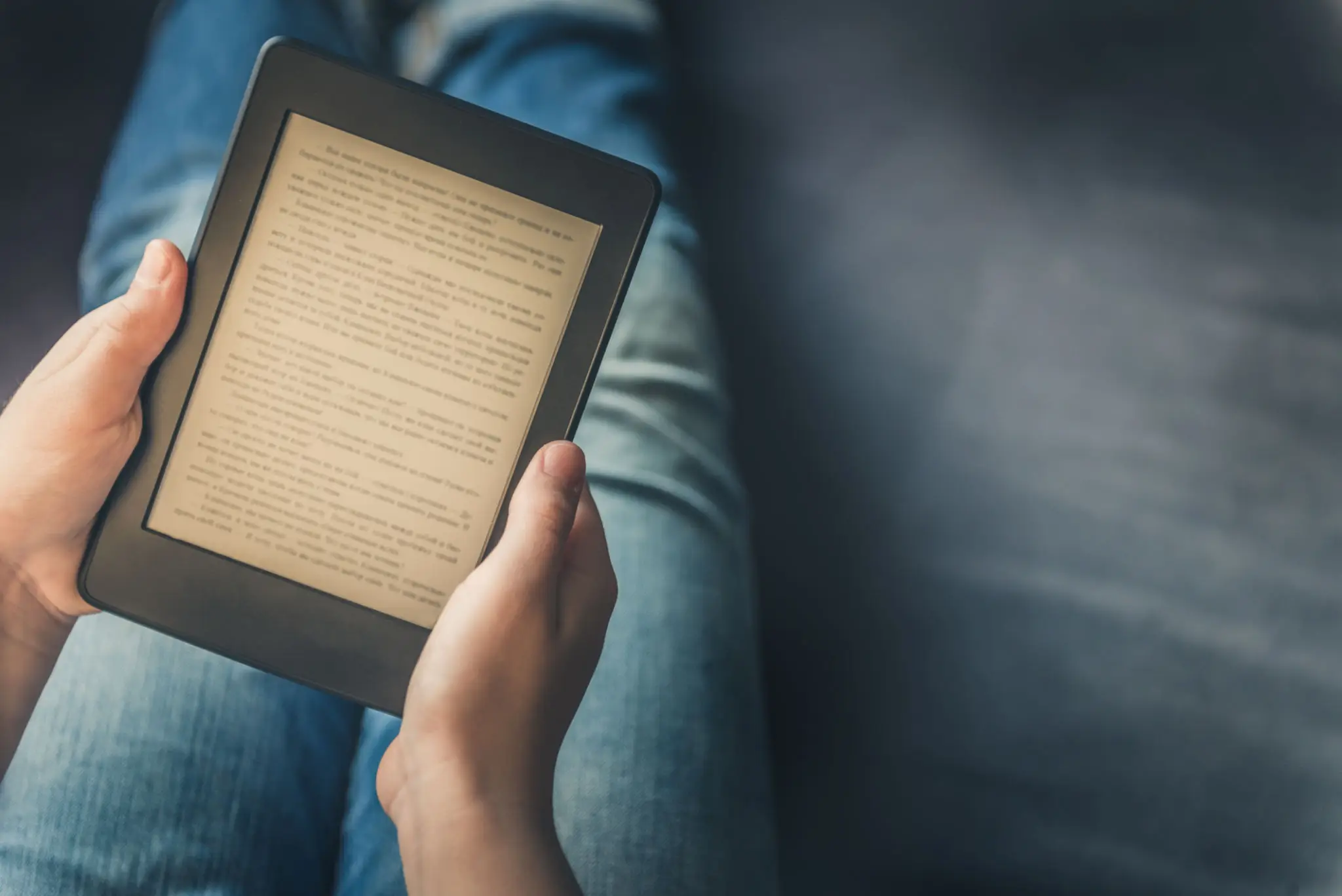 Person reading an e-book on a digital tablet while sitting.