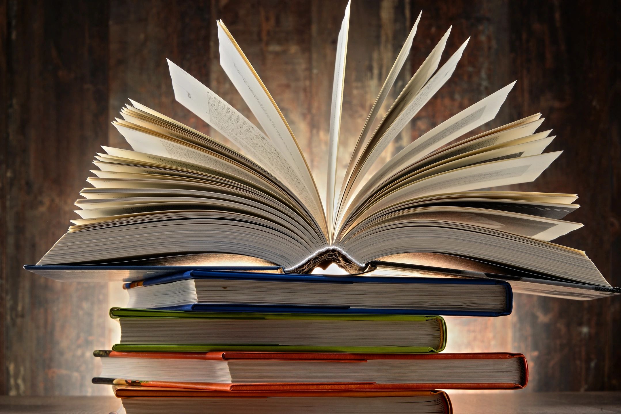 Open book on stack of colorful books.